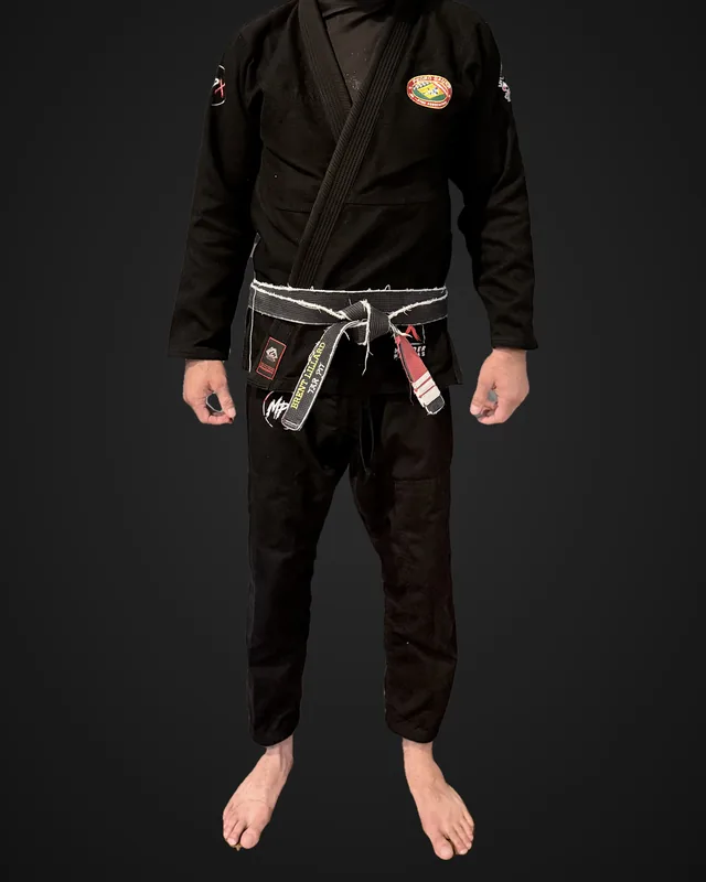 Front of Brent's black Murder Pajamas gi after 20 wash and dry cycles, worn and cropped at the collar, with his own gym chest patch and belt