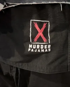 Close-up of the embroidered red X and Murder Pajamas patch on the black gi jacket skirt after 20 washes